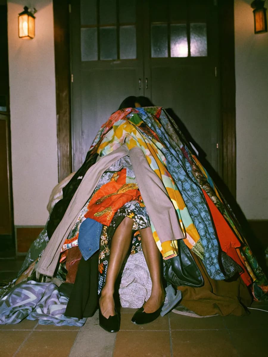 Person under clothes pile